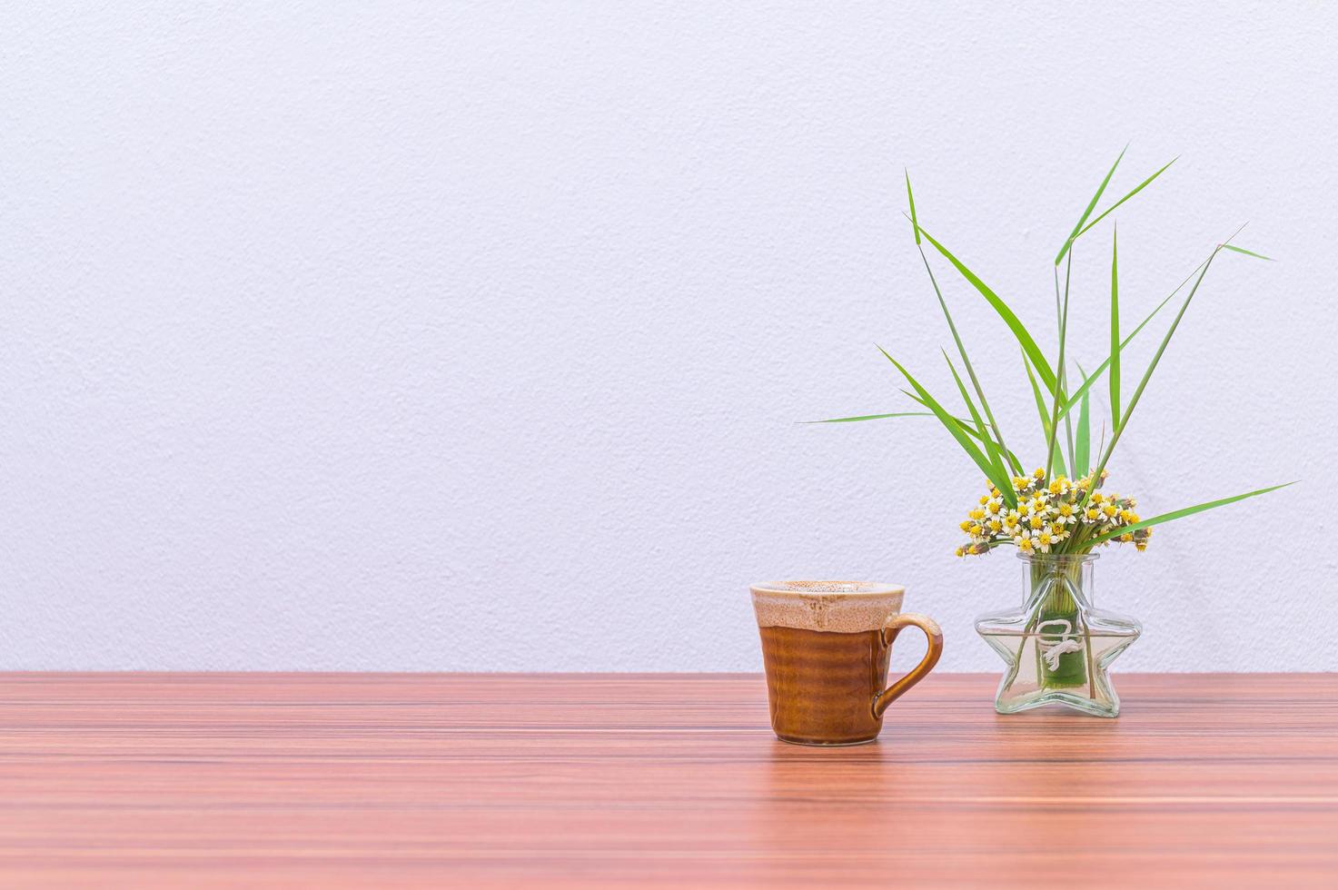 caneca de café e vaso de flores na mesa foto