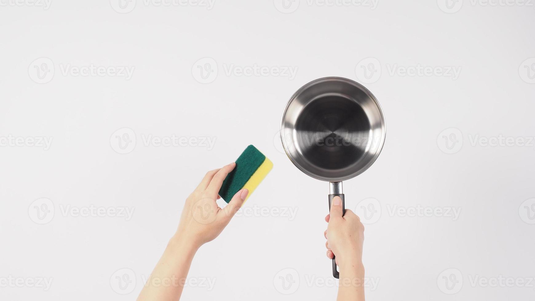 mão de homem de limpeza de pote em fundo branco limpando o pote antiaderente com esponja de lavar louça prática que cor amarela no lado macio e verde no lado duro para higiene após o cozimento. panela elétrica foto