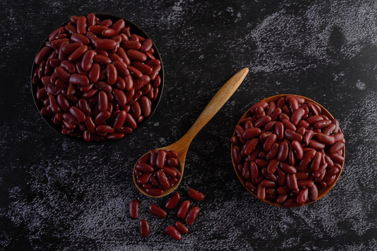 feijão vermelho em tigelas de madeira na superfície preta da cozinha foto