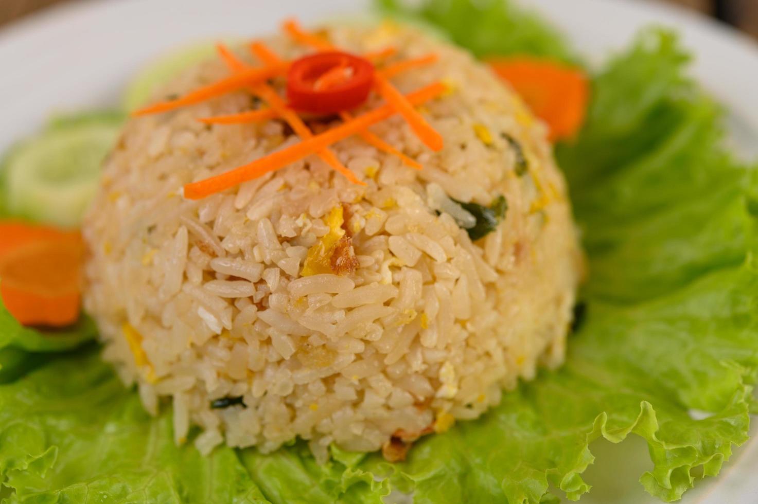 arroz frito em um prato branco com alface e enfeite foto