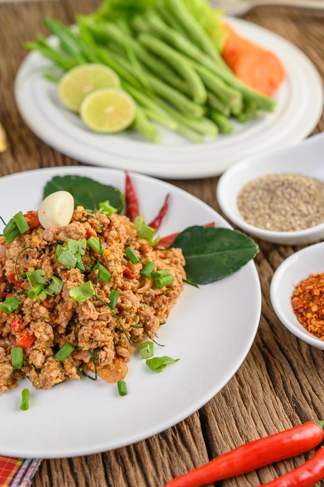 Salada de porco picada com especiarias em uma mesa de madeira foto