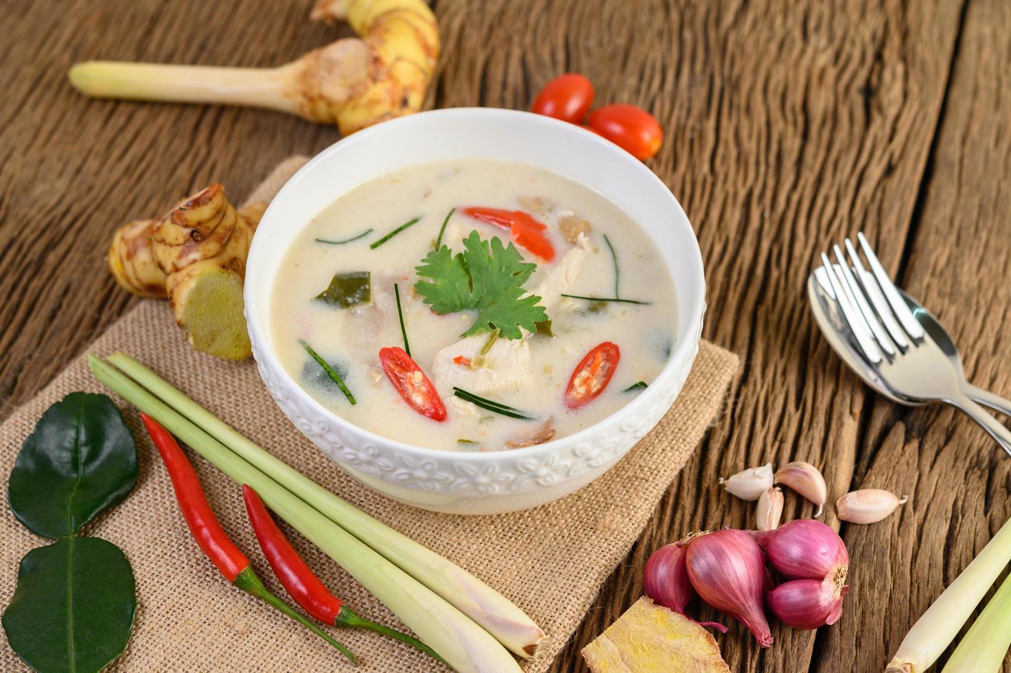 tom kha kai, sopa de coco tailandesa na mesa de madeira da cozinha foto