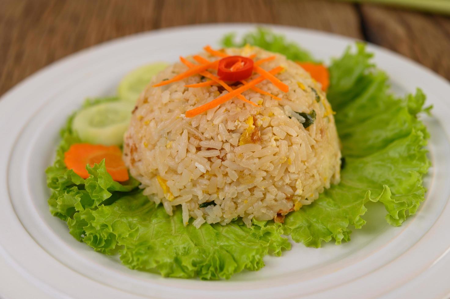 arroz frito em um prato branco com alface e enfeite foto
