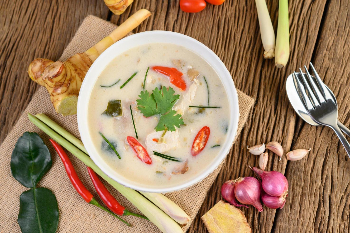 tom kha kai, sopa de coco tailandesa na mesa de madeira da cozinha foto