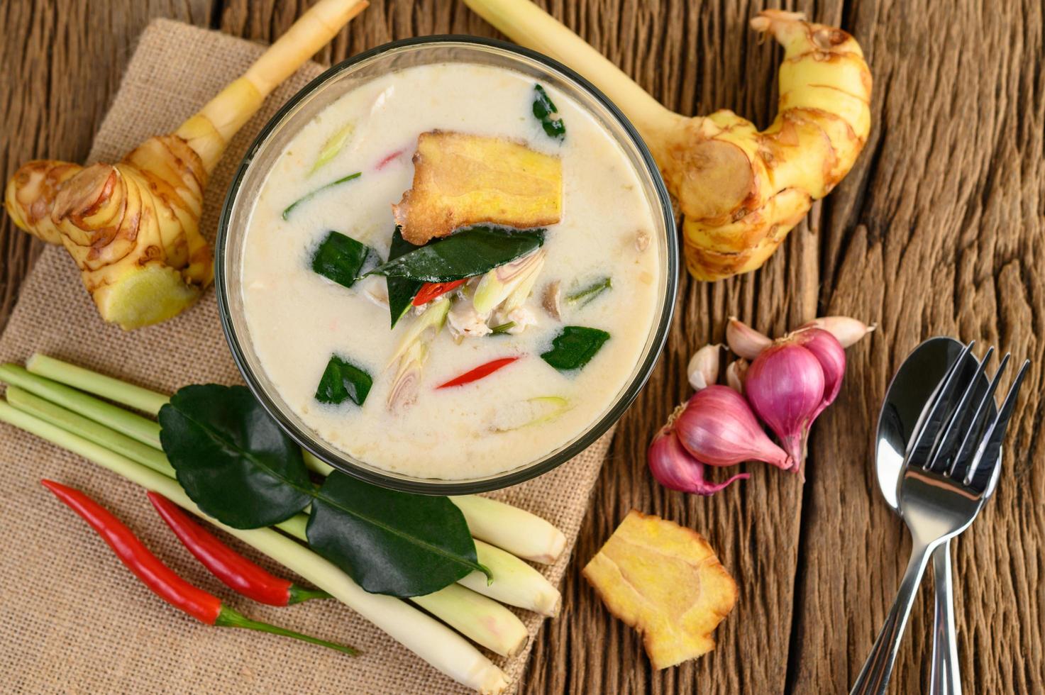 tom kha kai, sopa de coco tailandesa na mesa de madeira da cozinha foto