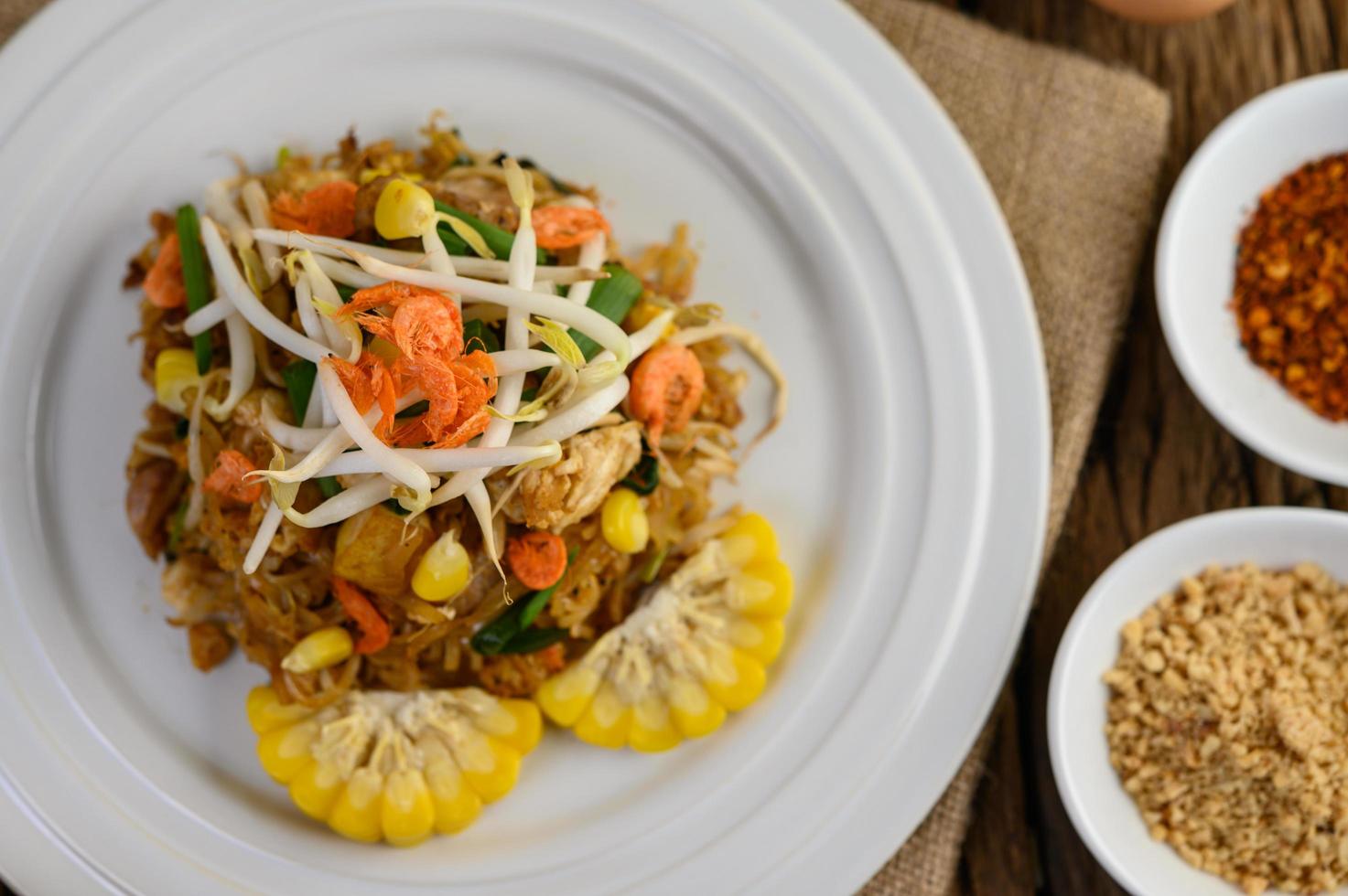 Pad thai com limão, ovos e temperos em uma mesa de madeira foto