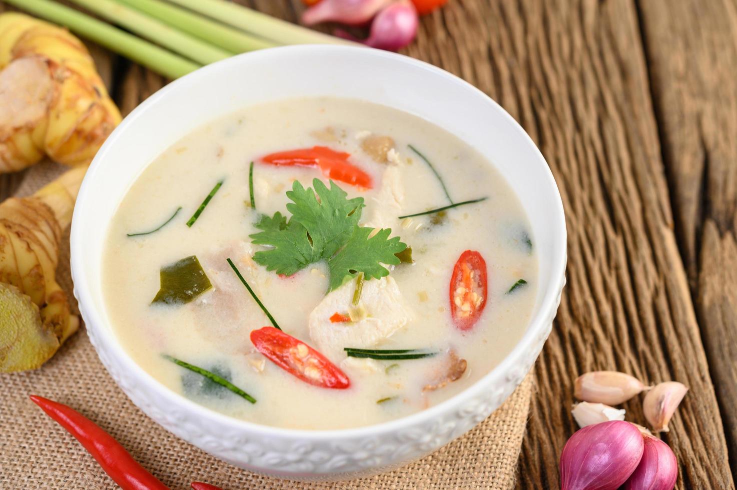 tom kha kai, sopa de coco tailandesa na mesa de madeira da cozinha foto