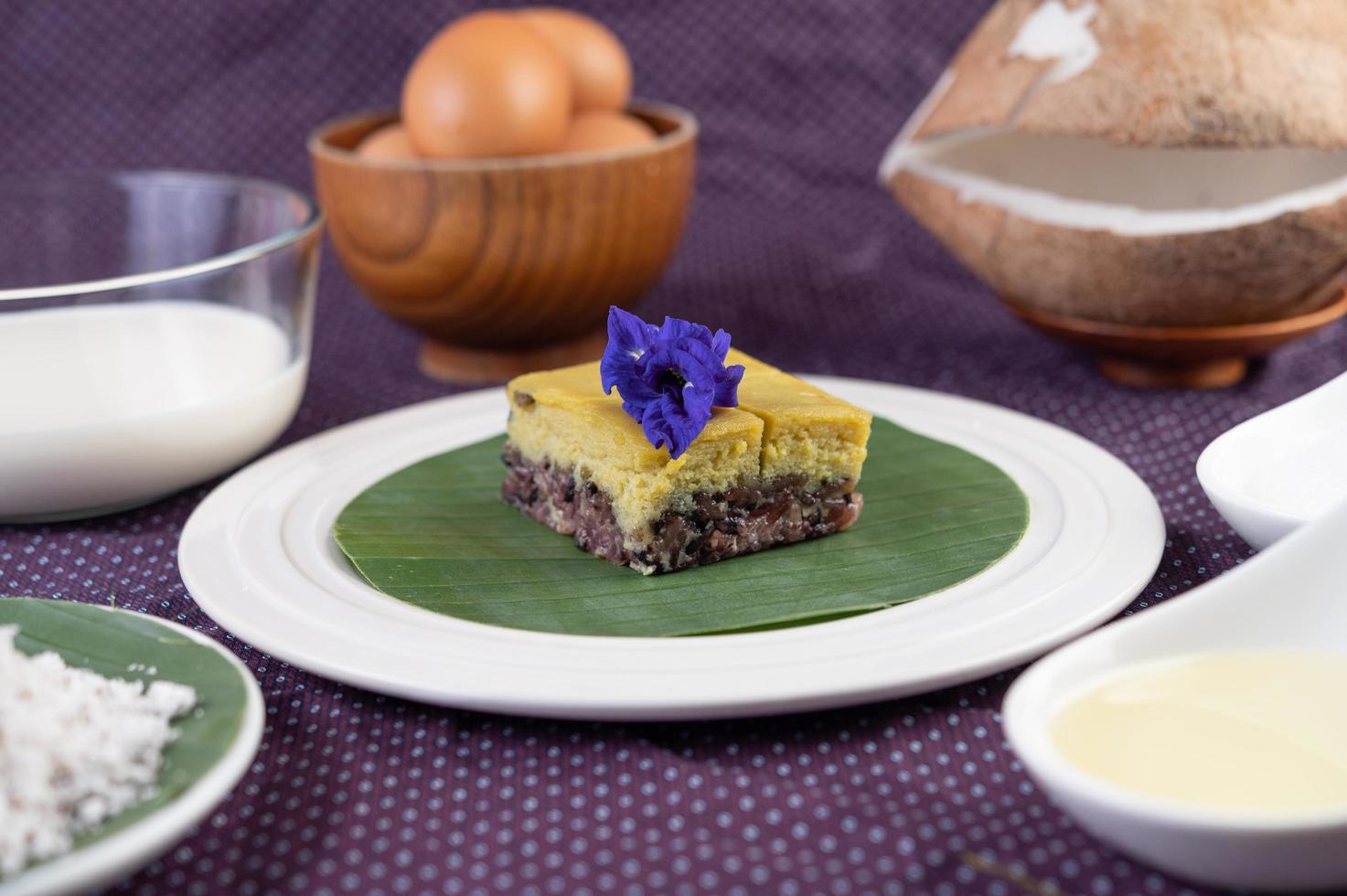 arroz preto pegajoso em uma folha de bananeira em um prato branco com flores de ervilha-borboleta foto