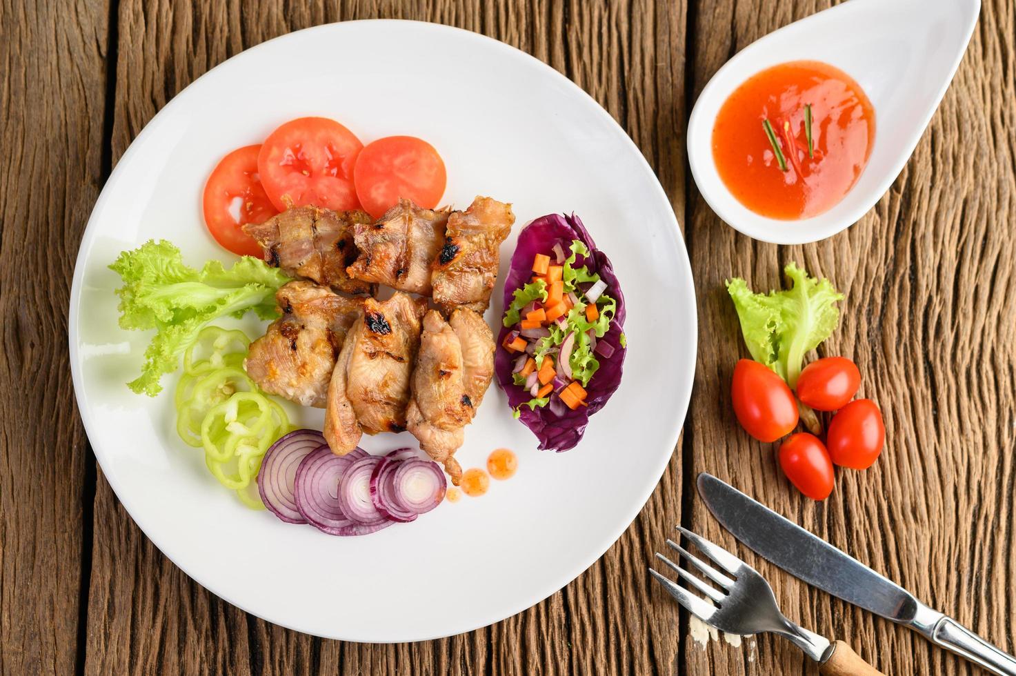 frango grelhado em uma tábua de madeira com salada foto