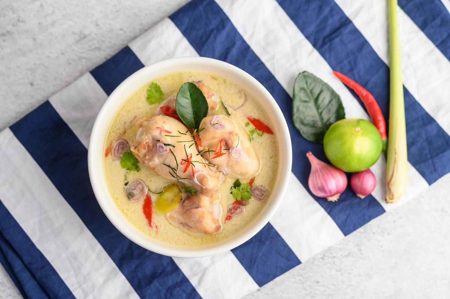 tom kha kai, sopa de coco tailandesa em um pano listrado de azul foto