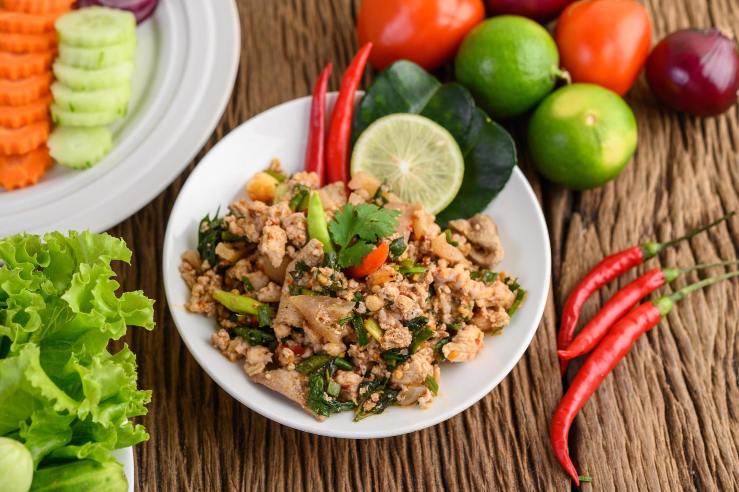 Salada de porco picada com especiarias em uma mesa de madeira foto