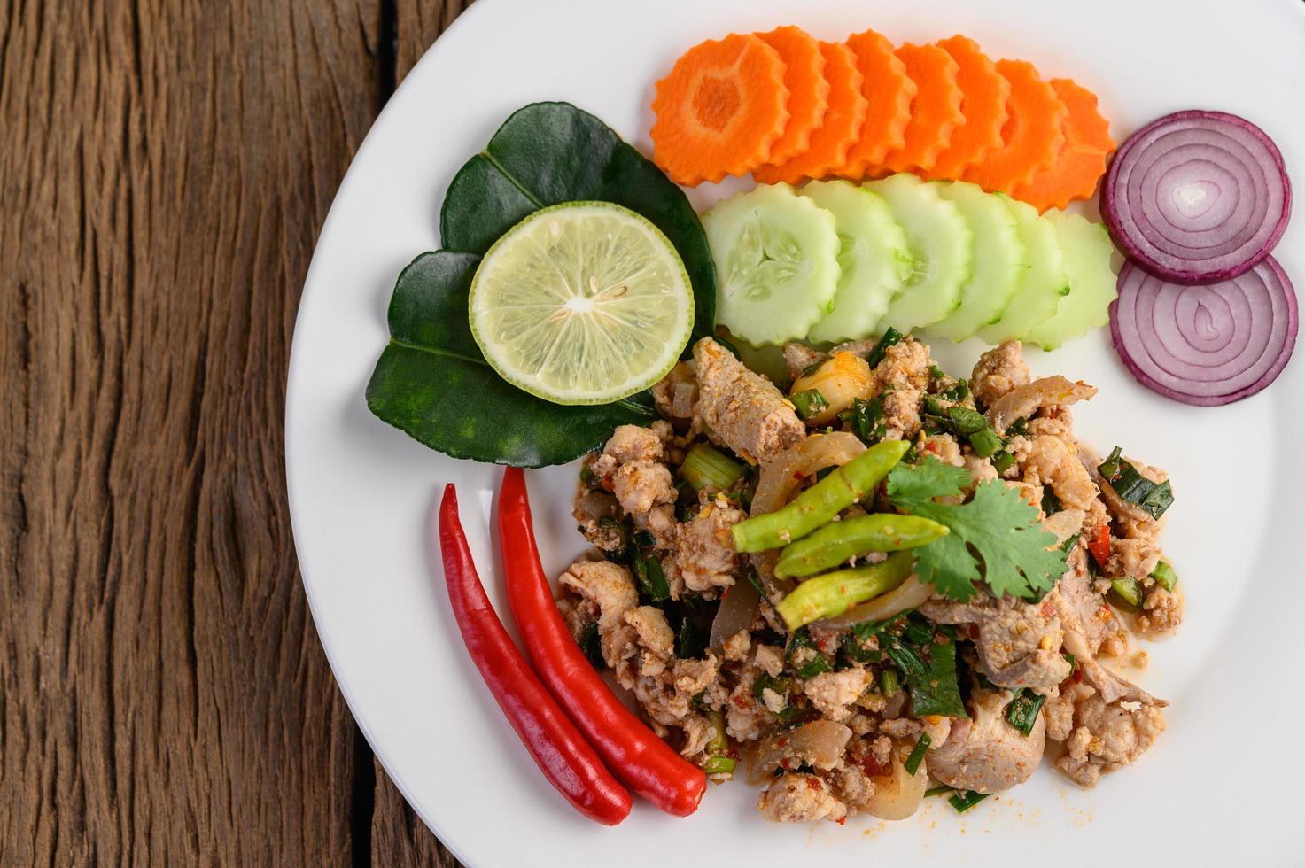 Salada de porco picada com especiarias em uma mesa de madeira foto