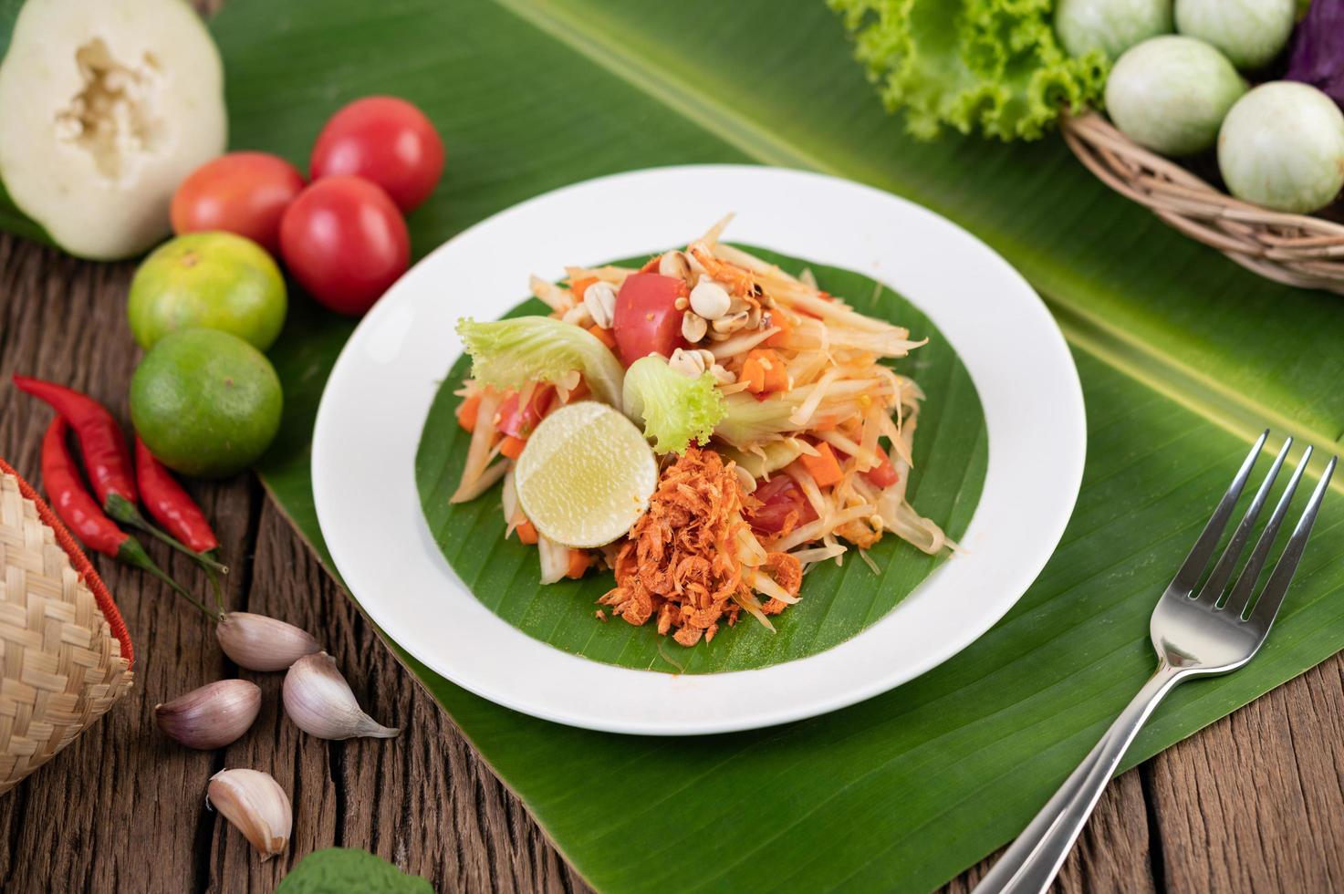 salada tailandesa de mamão com folhas de bananeira e ingredientes frescos foto