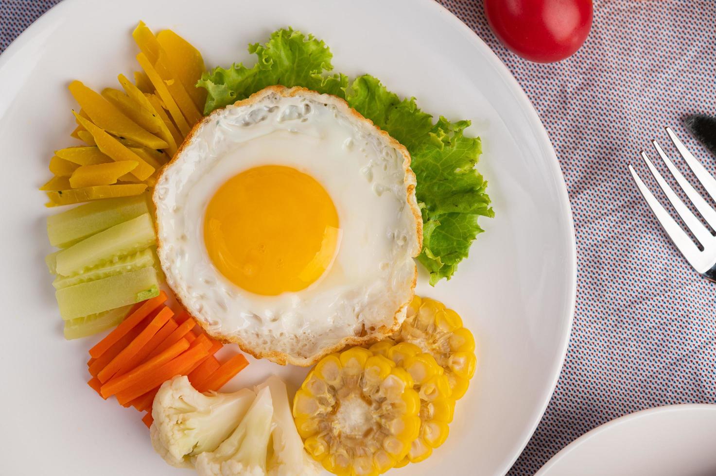 ovo frito, salada, abóbora, pepino, cenoura, milho, couve-flor, tomate e torrada foto