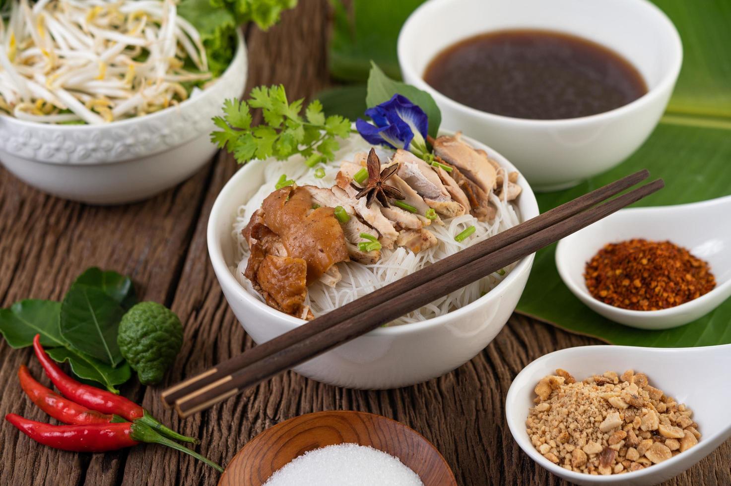 macarrão de frango em uma tigela com acompanhamentos tailandeses foto