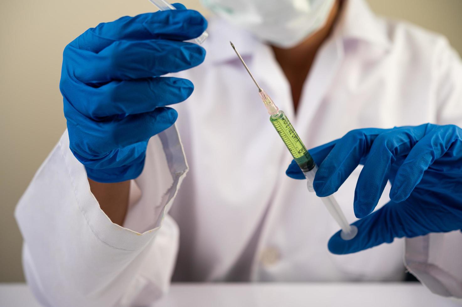 cientistas usando máscaras e luvas segurando uma seringa com uma vacina covid-19 foto
