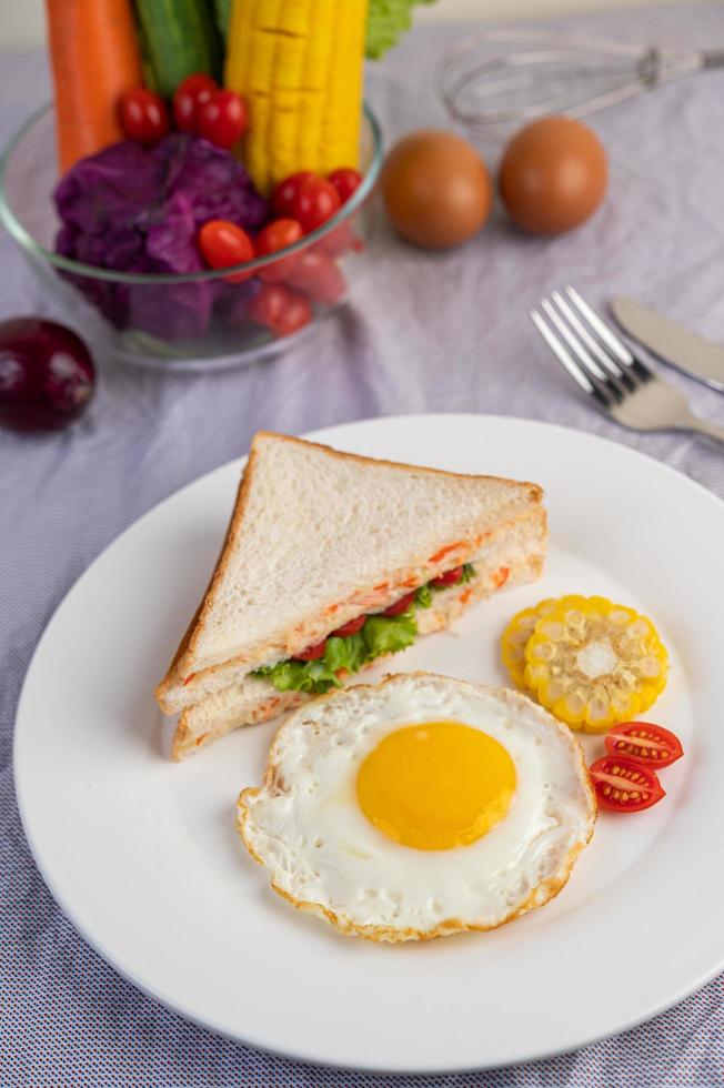 ovo frito café da manhã com ovo, salada, abóbora, pepino, cenoura e milho foto