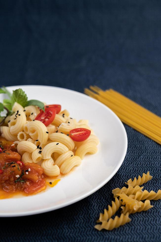 prato de macarrão com tomate, pimenta, sementes de pimenta e manjericão foto