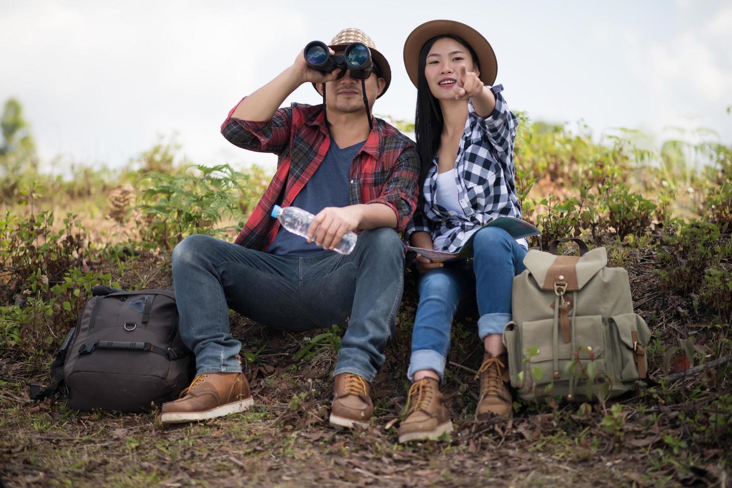 casal jovem olhando mapa enquanto caminha na floresta foto