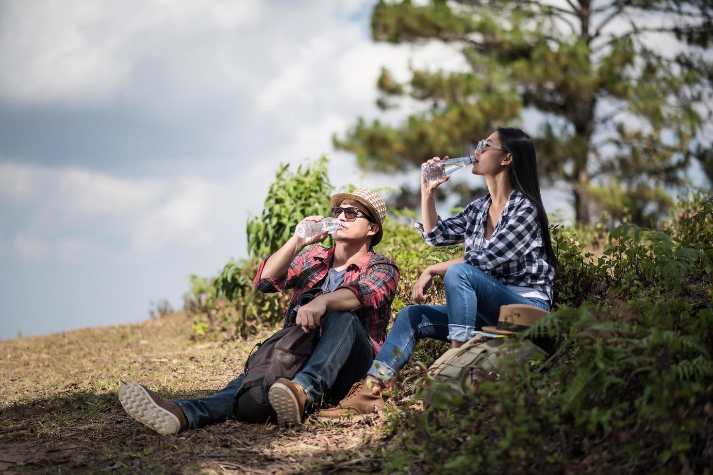 jovens caminhantes bebendo água na floresta foto