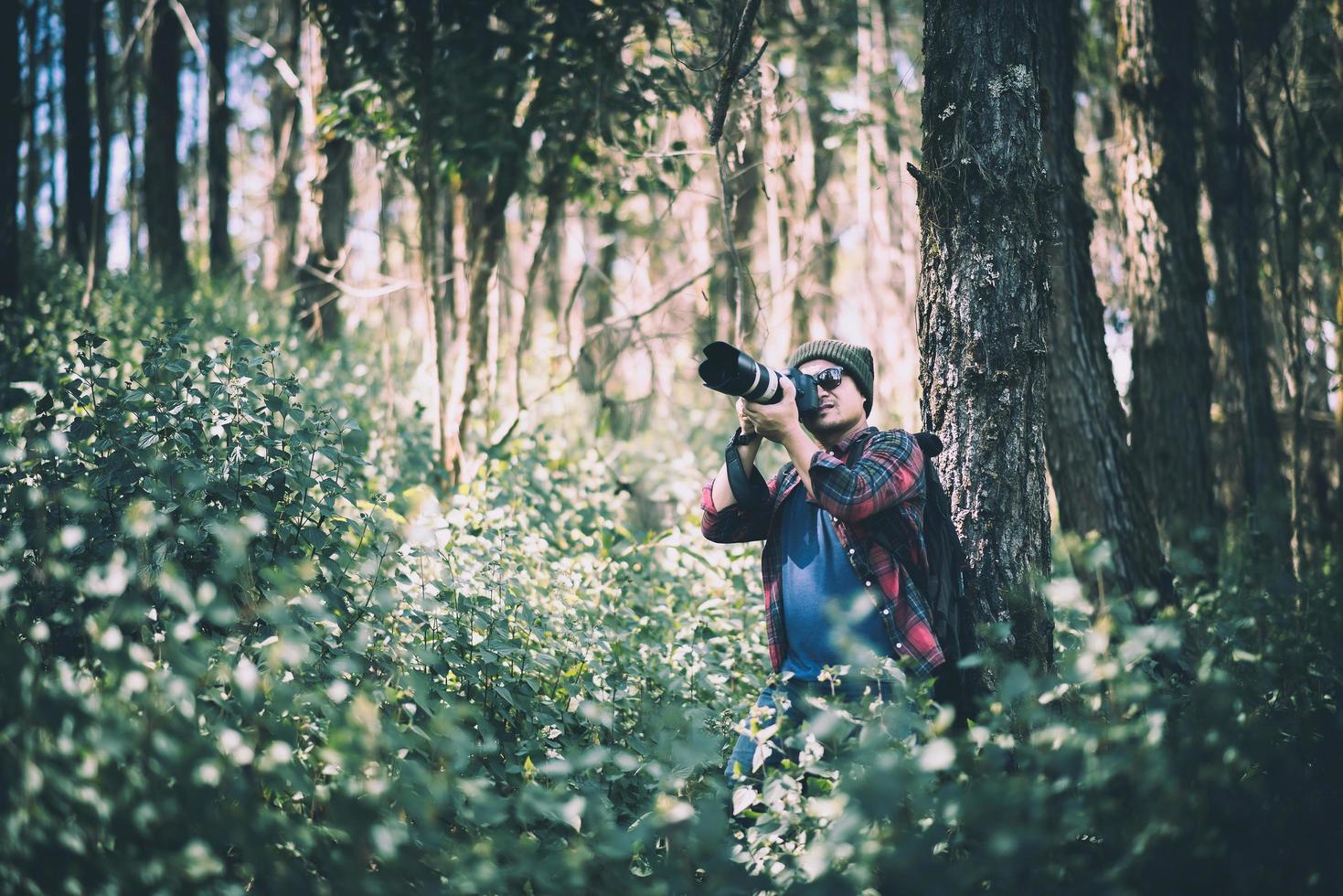 jovem fotógrafo tirando fotos na floresta