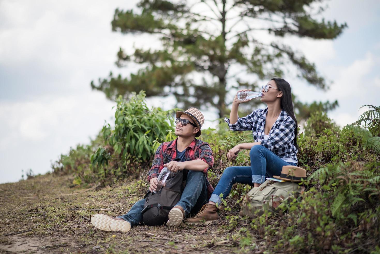 jovens caminhantes bebendo água na floresta foto