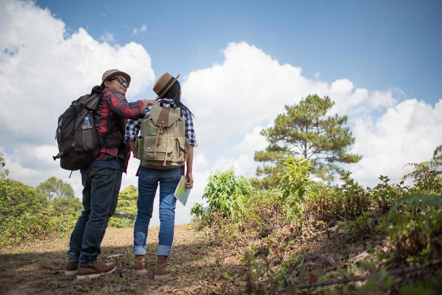 jovem casal caminhando com mochilas na floresta foto