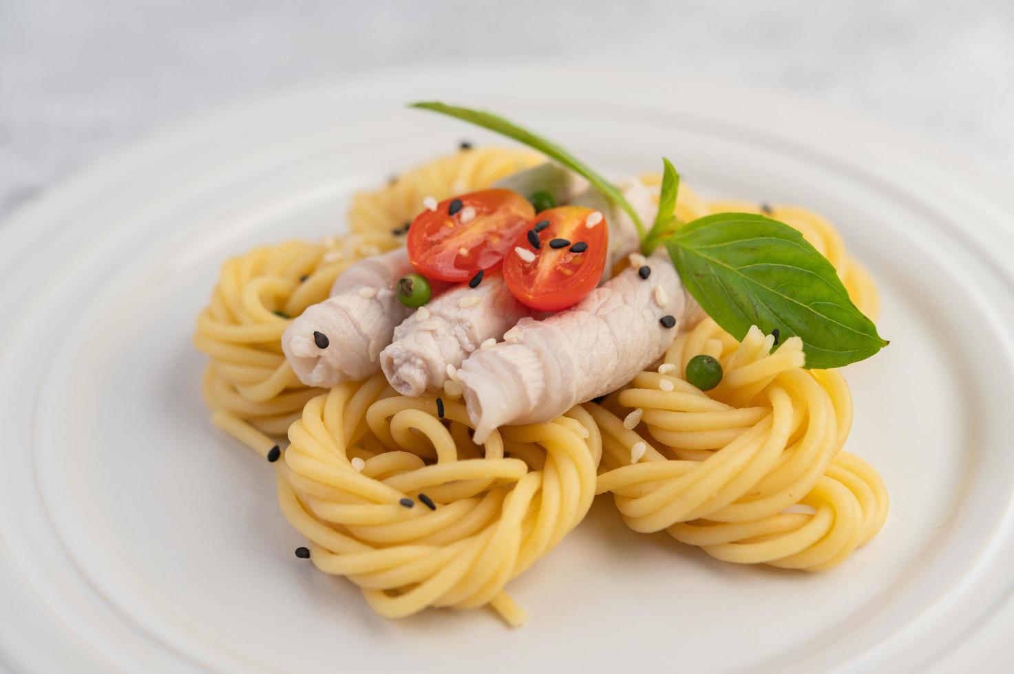 espaguete e carne de porco banhados em um prato branco foto