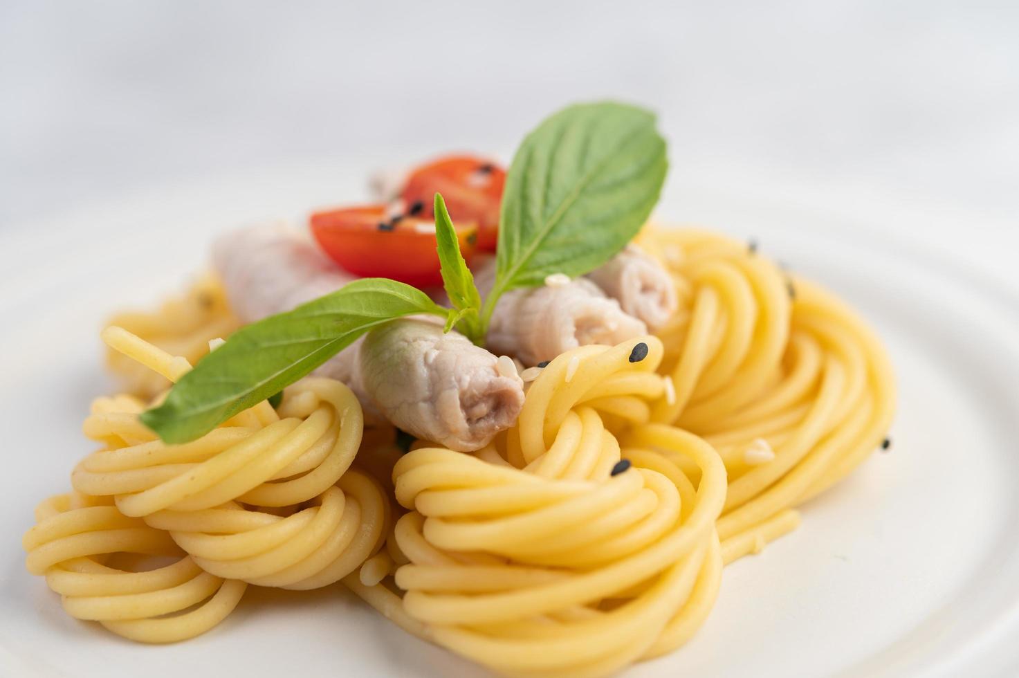 espaguete e carne de porco banhados em um prato branco foto