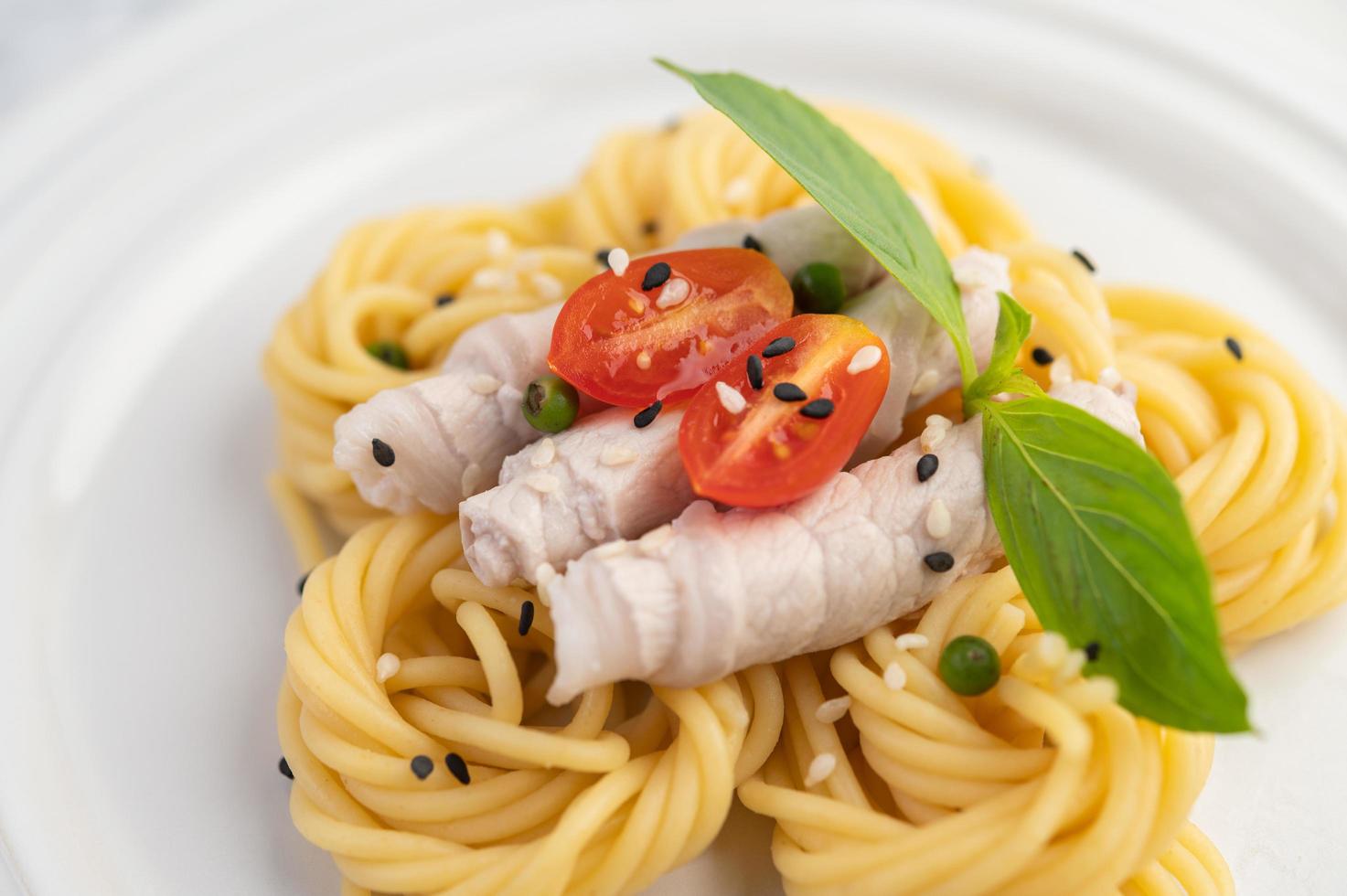 espaguete e carne de porco banhados em um prato branco foto