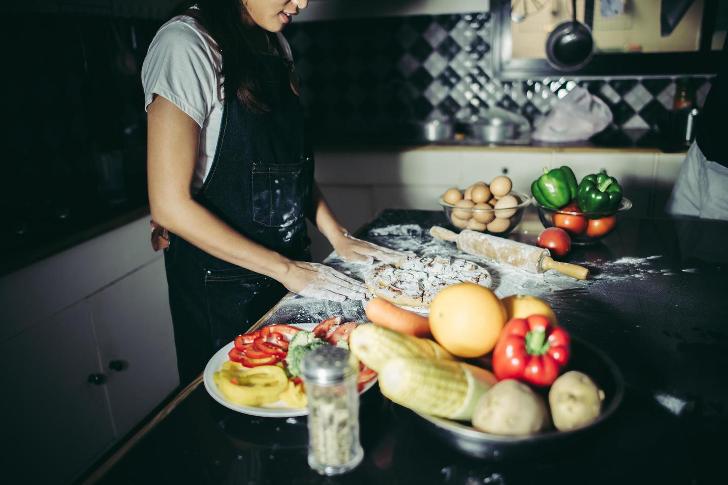 mulher cozinhando pizza caseira em casa foto