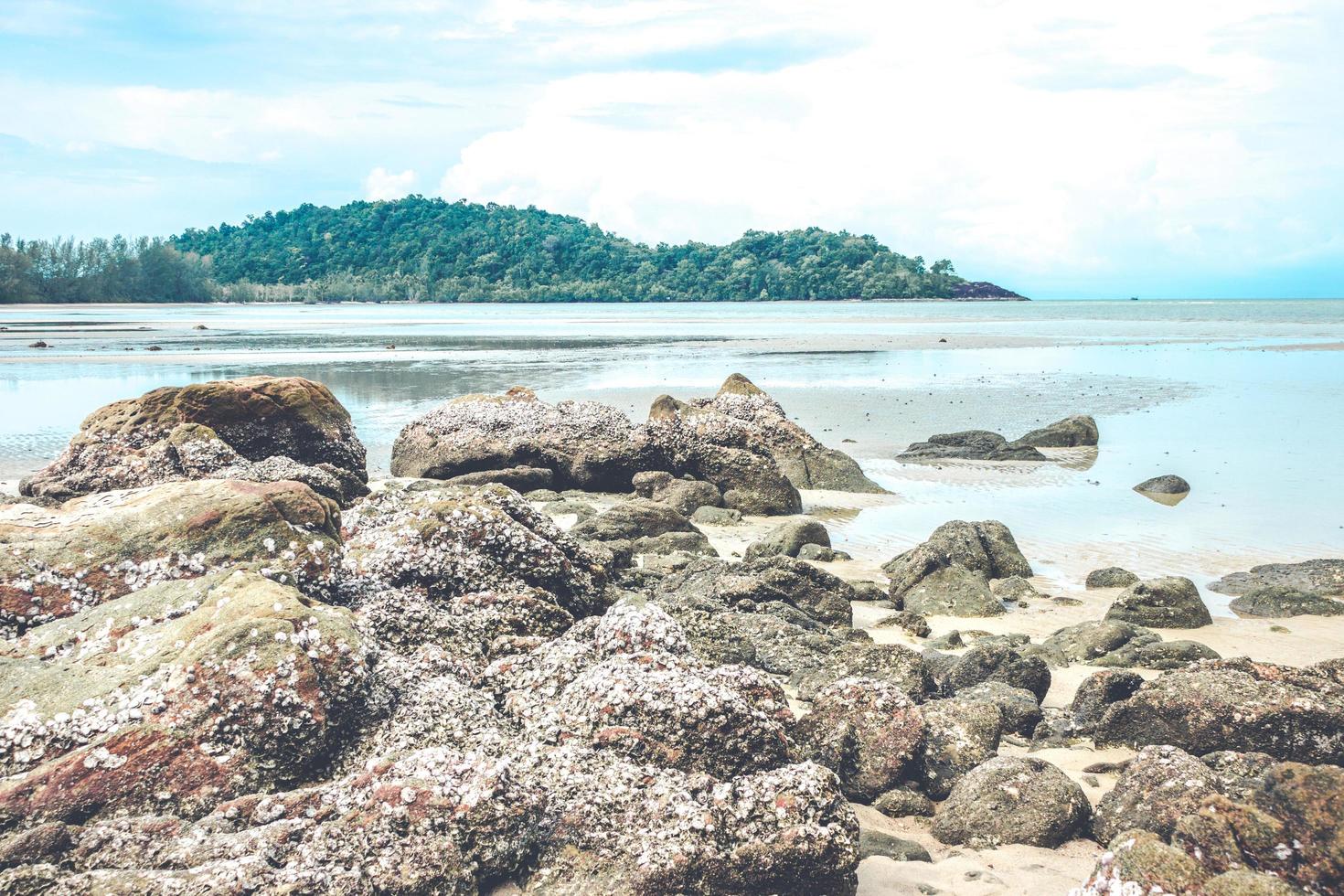 rochas na praia com céu azul nublado foto