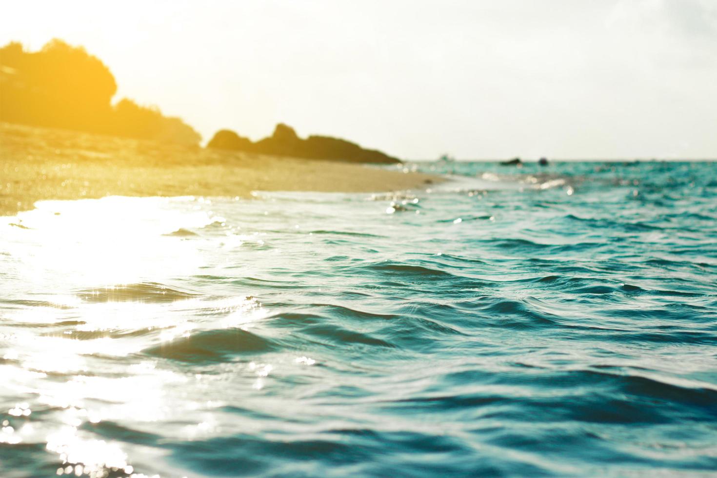 areia e água na praia com céu azul claro foto