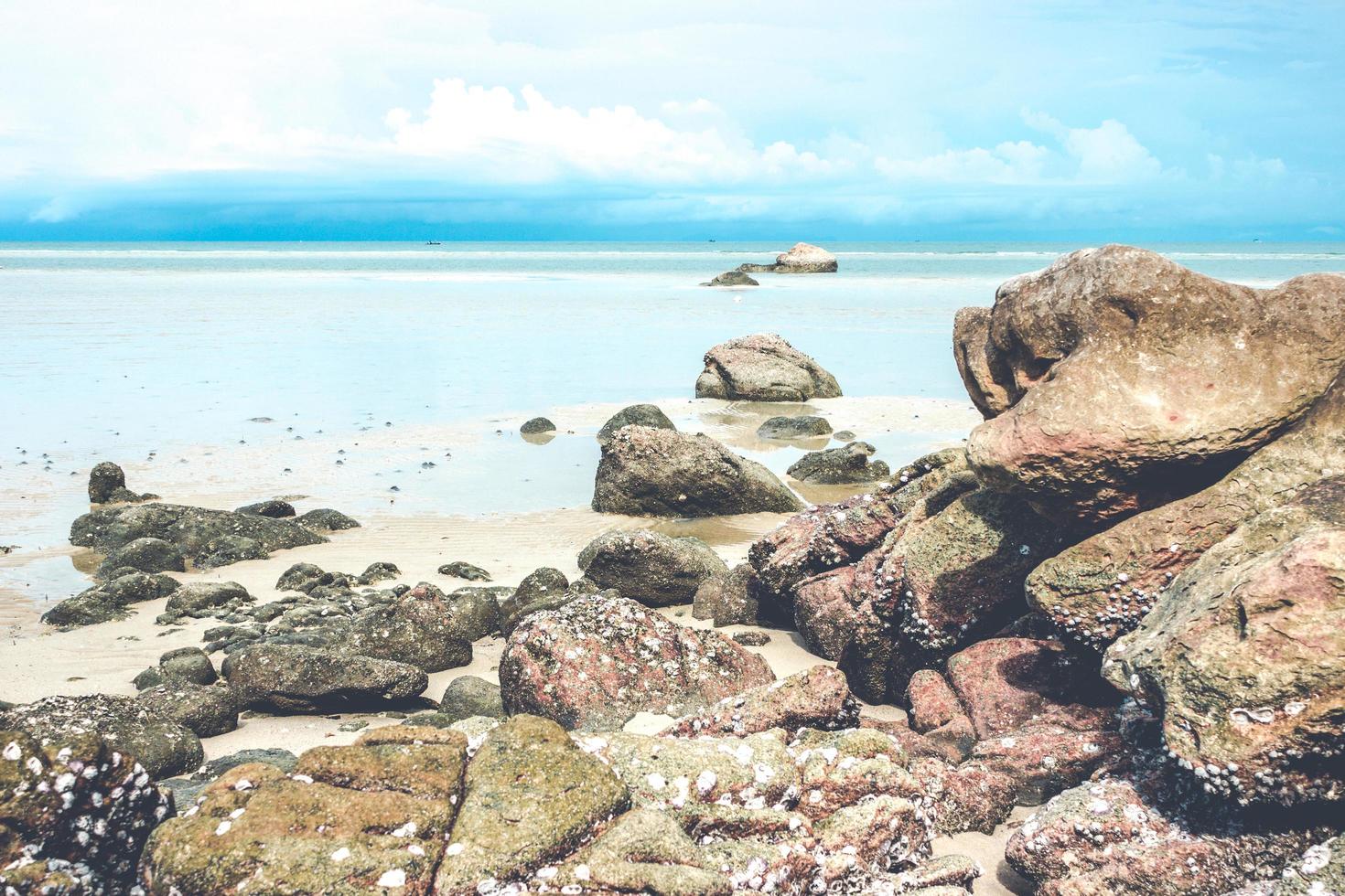 rochas na praia com céu azul nublado foto