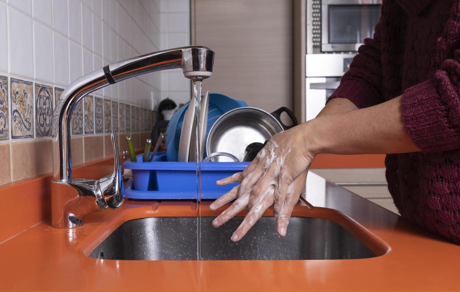 mulher lavando as mãos na cozinha foto