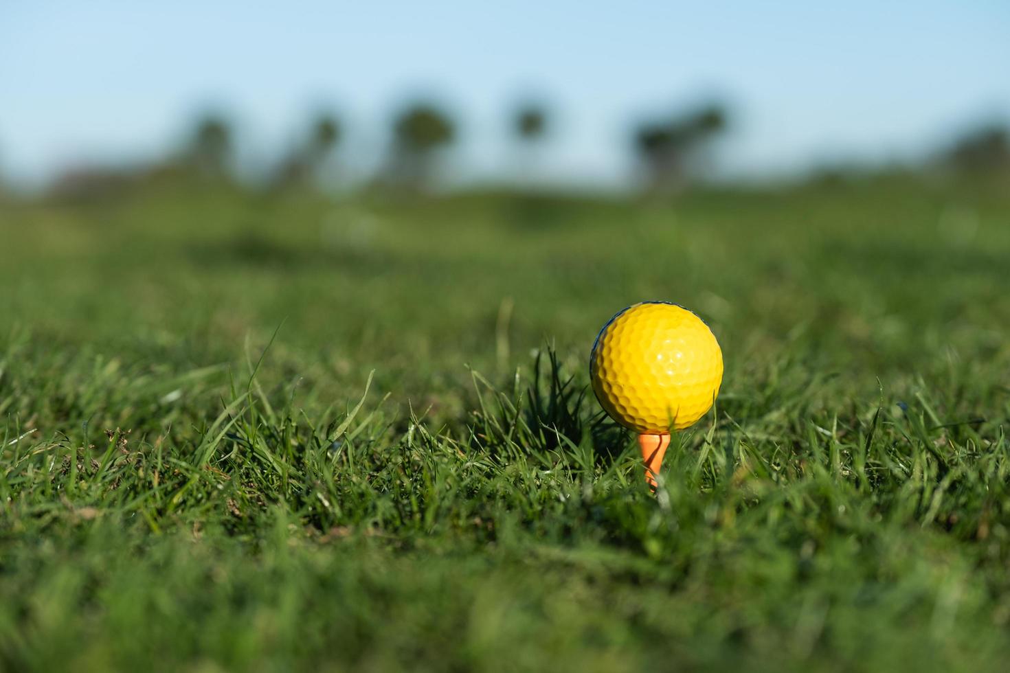 bola de golfe amarela no chão no driving range foto