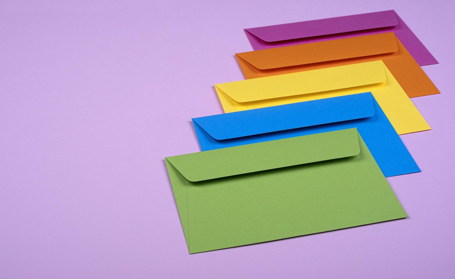 envelopes coloridos bem organizados em um fundo rosa claro foto