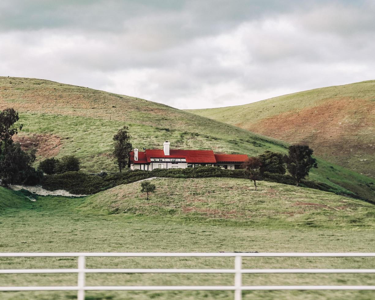 utah, 2020 - casa vermelha e branca em campo de grama verde perto de uma montanha sob nuvens brancas durante o dia foto