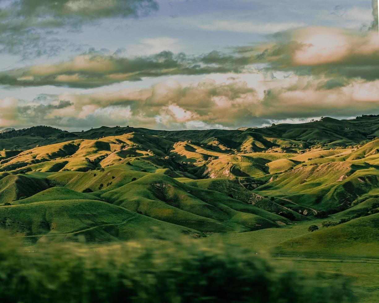 montanhas verdes sob nuvens brancas durante o dia foto