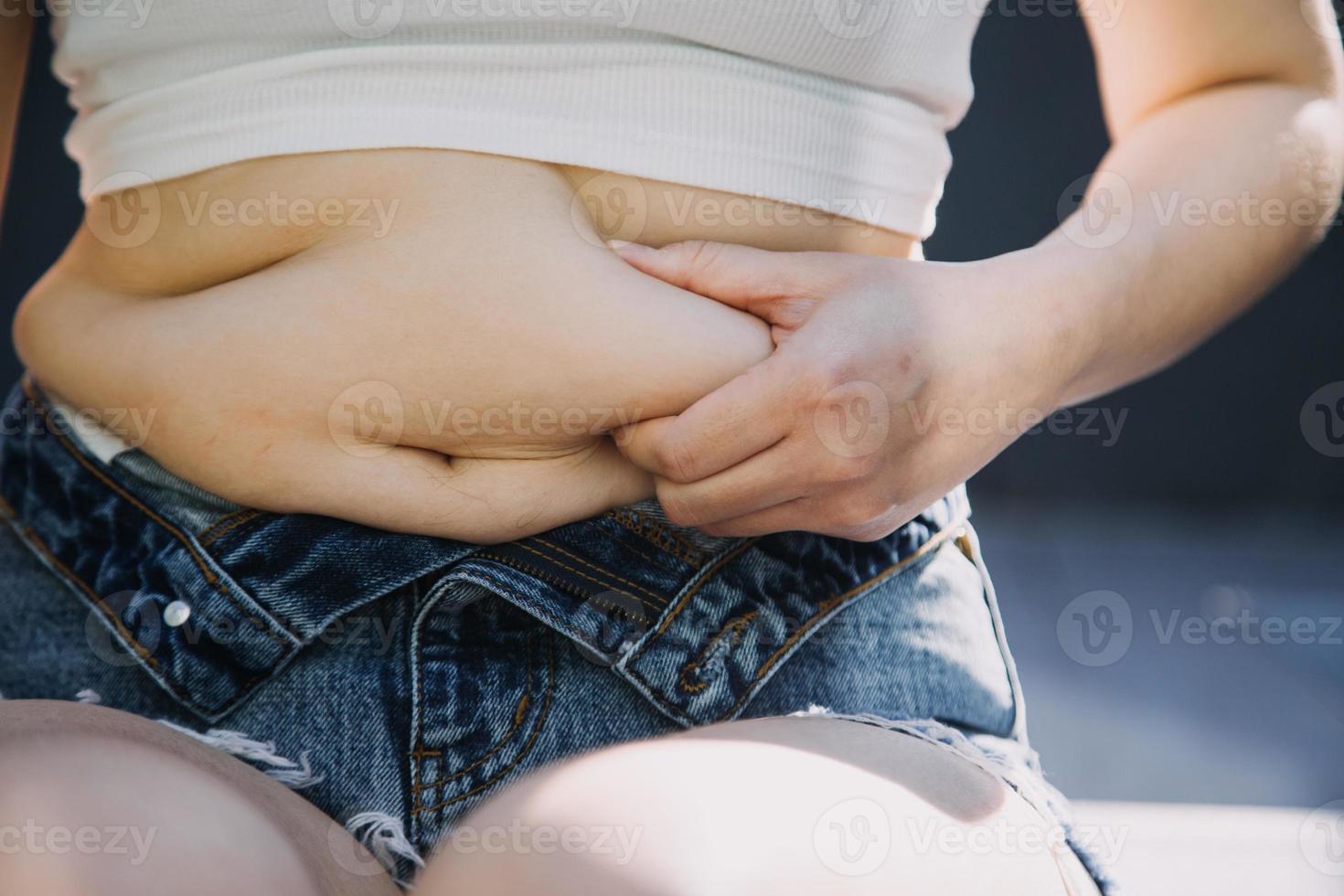 mulher gorda, barriga gorda, gordinha, mão de mulher obesa segurando gordura excessiva da barriga com fita métrica, conceito de estilo de vida de dieta de mulher foto