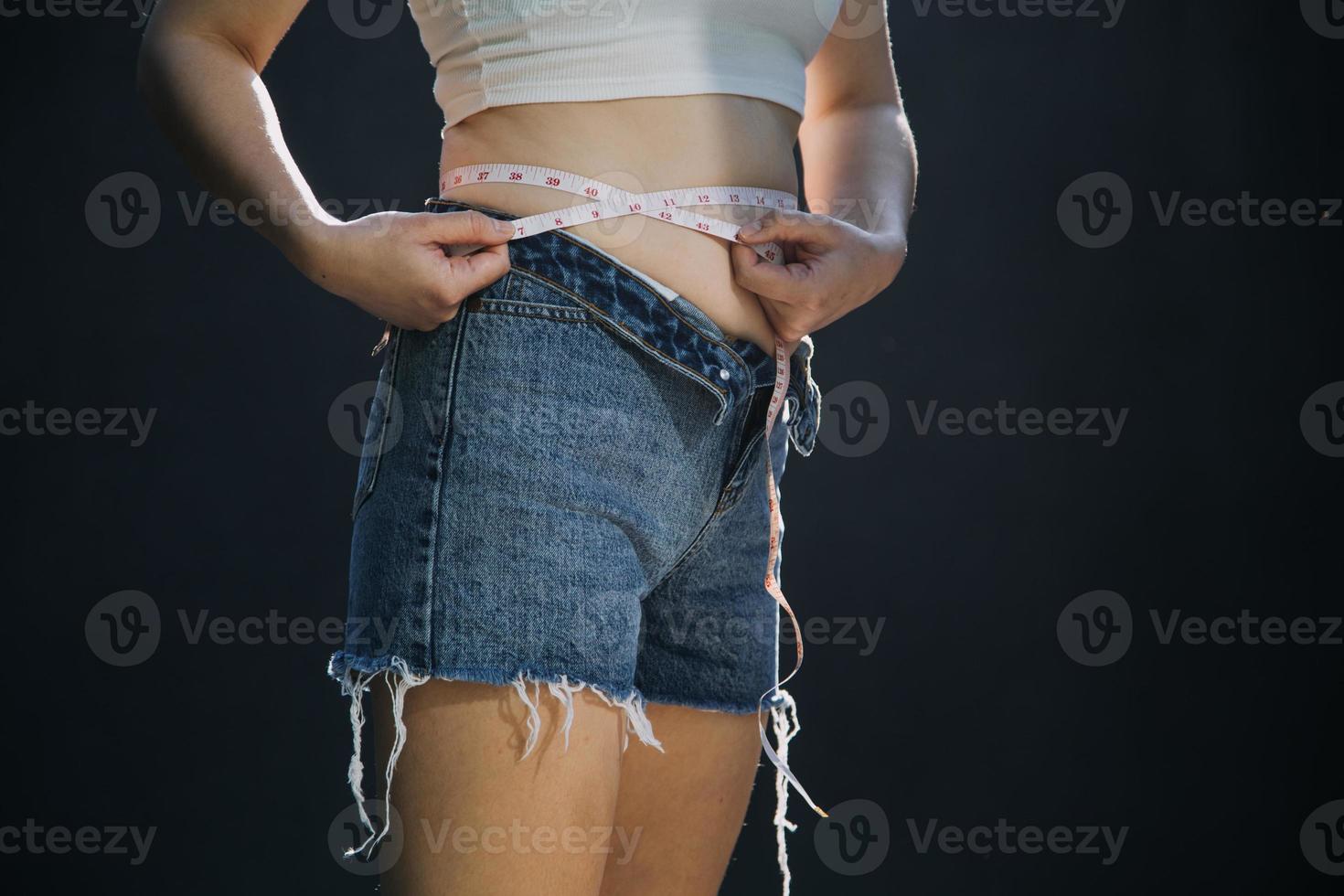 mulher gorda, barriga gorda, gordinha, mão de mulher obesa segurando gordura excessiva da barriga com fita métrica, conceito de estilo de vida de dieta de mulher foto