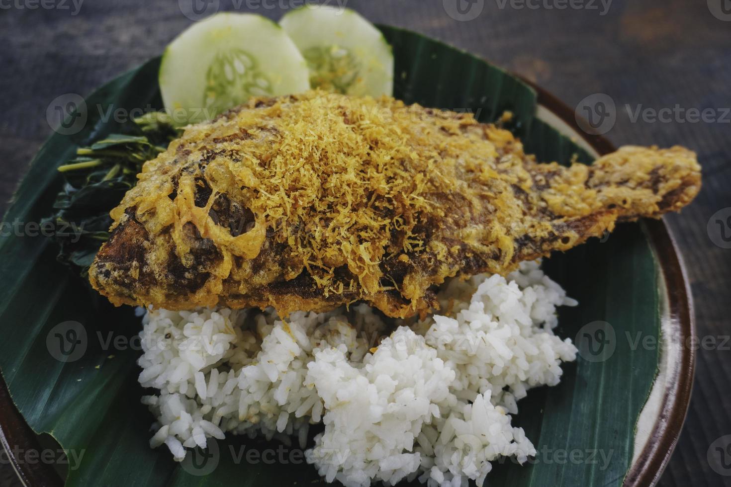 um retrato de uma tilápia frita com arroz, legumes ou lalapan e molho de pimenta ou sambal foto