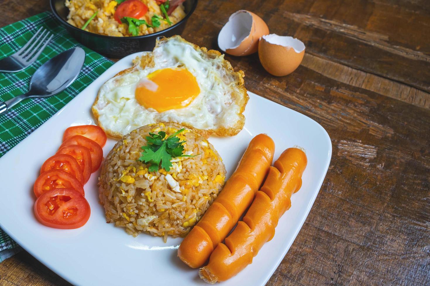 arroz frito americano servido com ovos fritos e salsichas na mesa foto