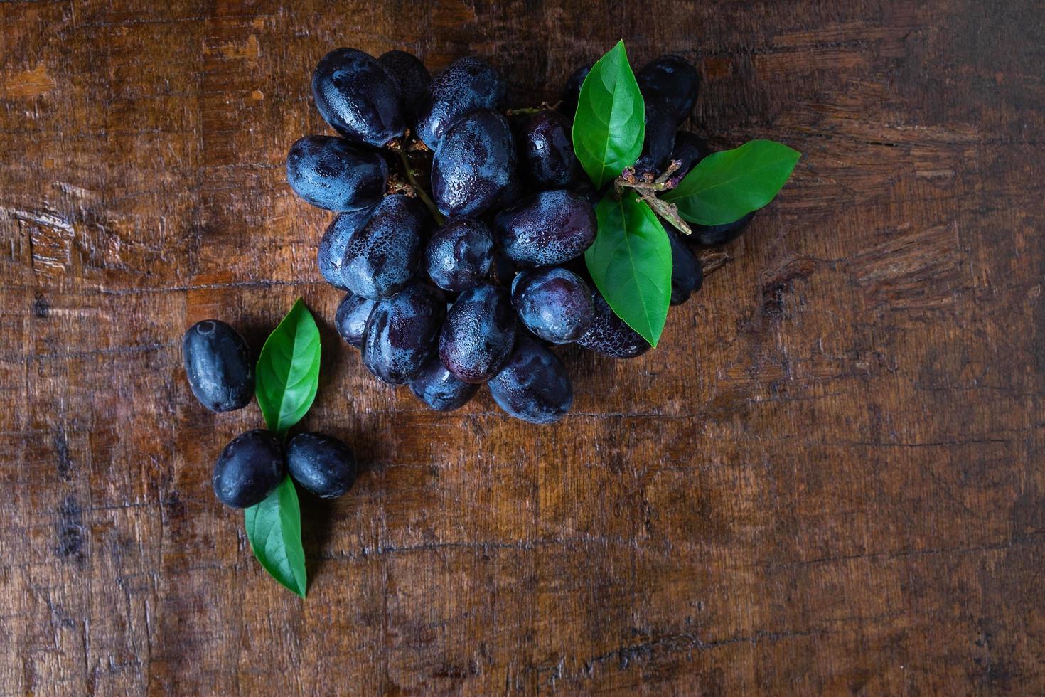 uvas pretas em uma mesa de madeira foto