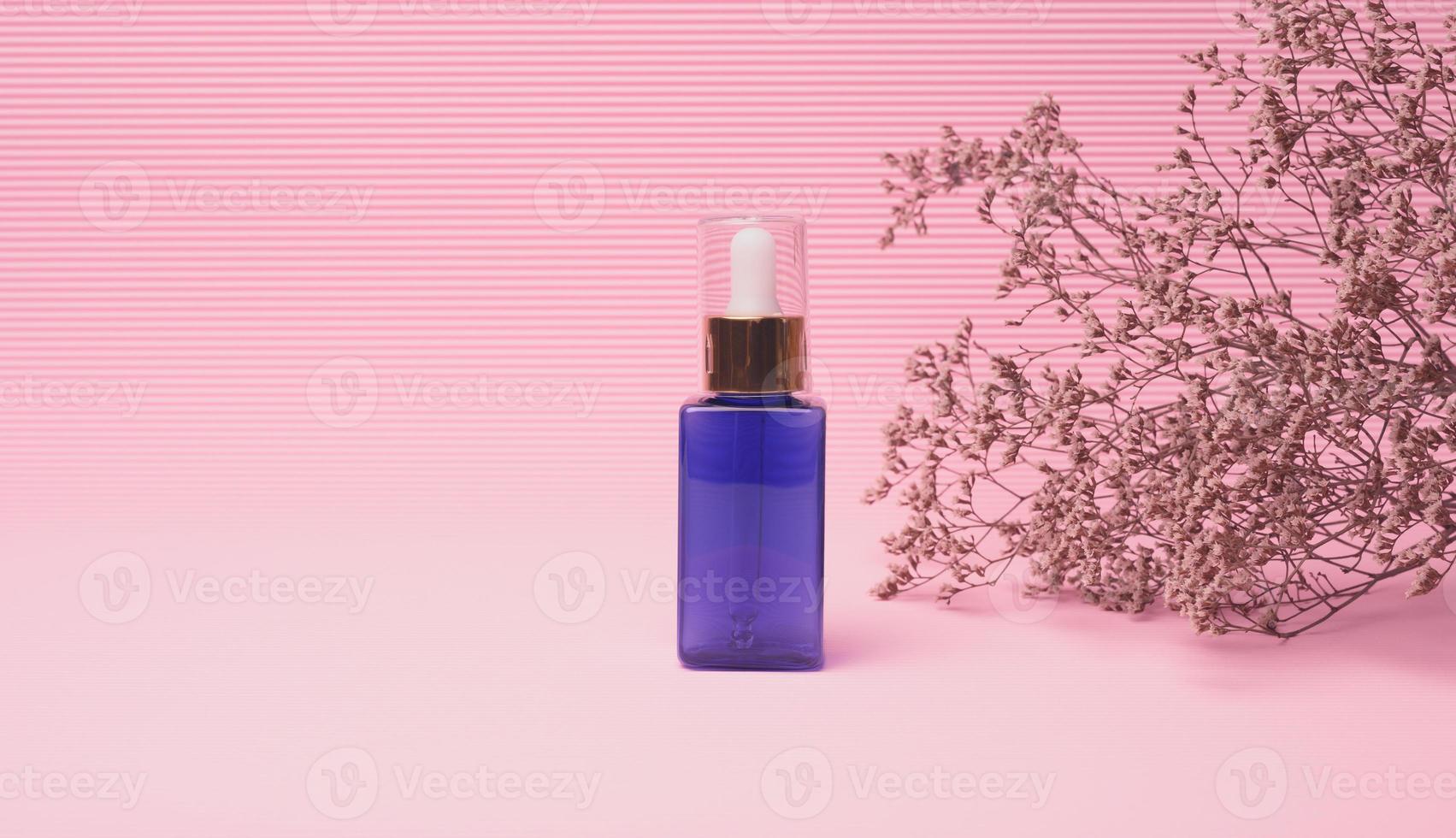 garrafa de vidro azul com um conta-gotas para cosméticos em um fundo rosa. embalagens para gel, soro, publicidade e promoção. produtos orgânicos naturais foto