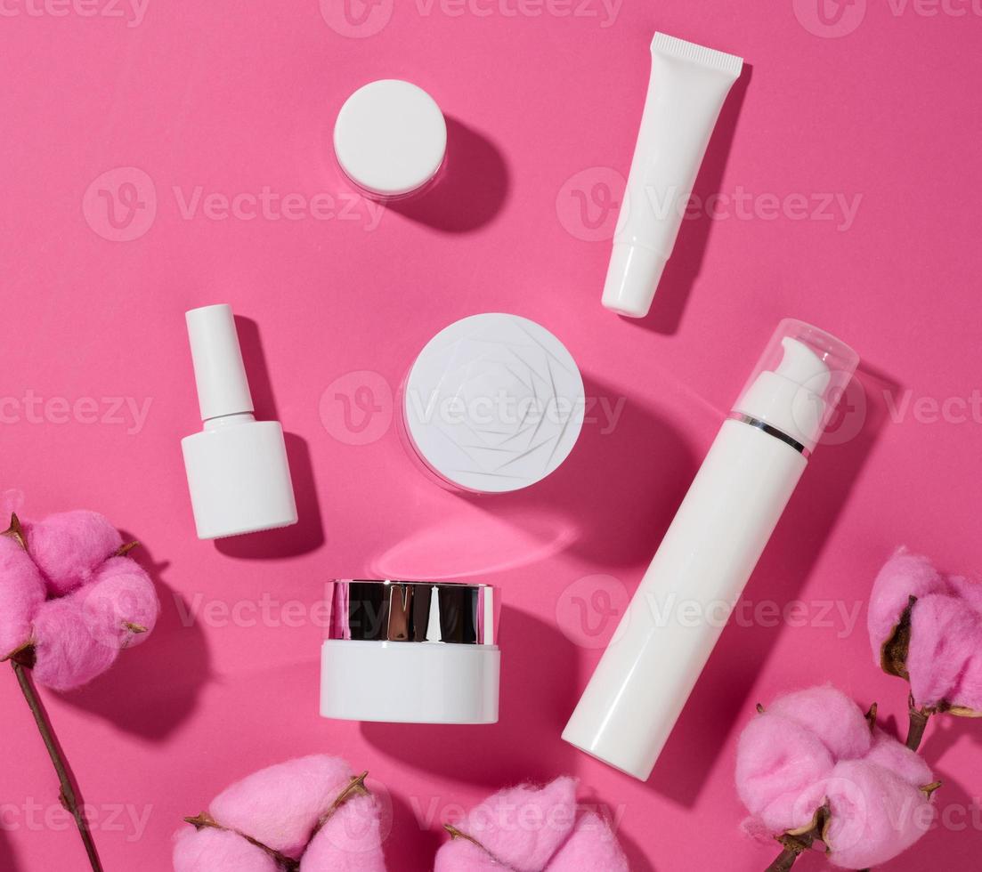 frasco e tubos de plástico brancos vazios para cosméticos em um fundo rosa. embalagem para creme, gel, soro, publicidade e promoção de produtos, vista superior foto