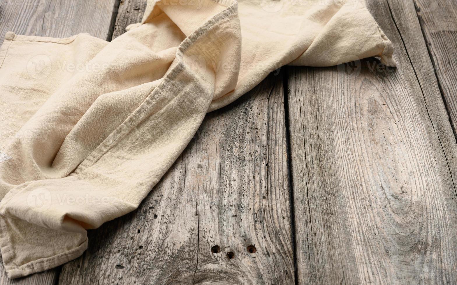 toalha de linho bege dobrada em uma mesa feita de velhas tábuas de madeira cinza, vista superior foto