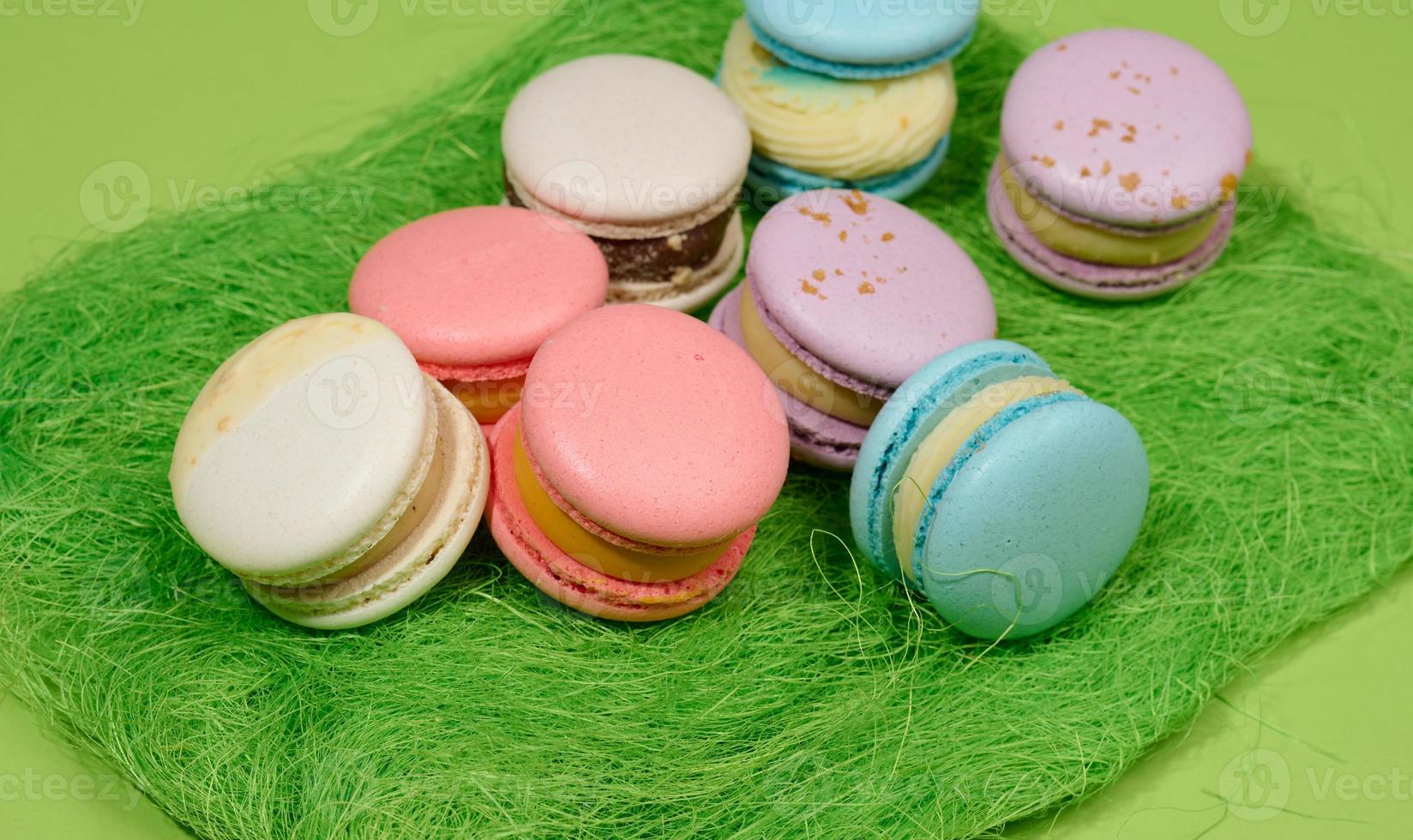 macarons assados com sabores diferentes em um fundo verde, vista superior foto