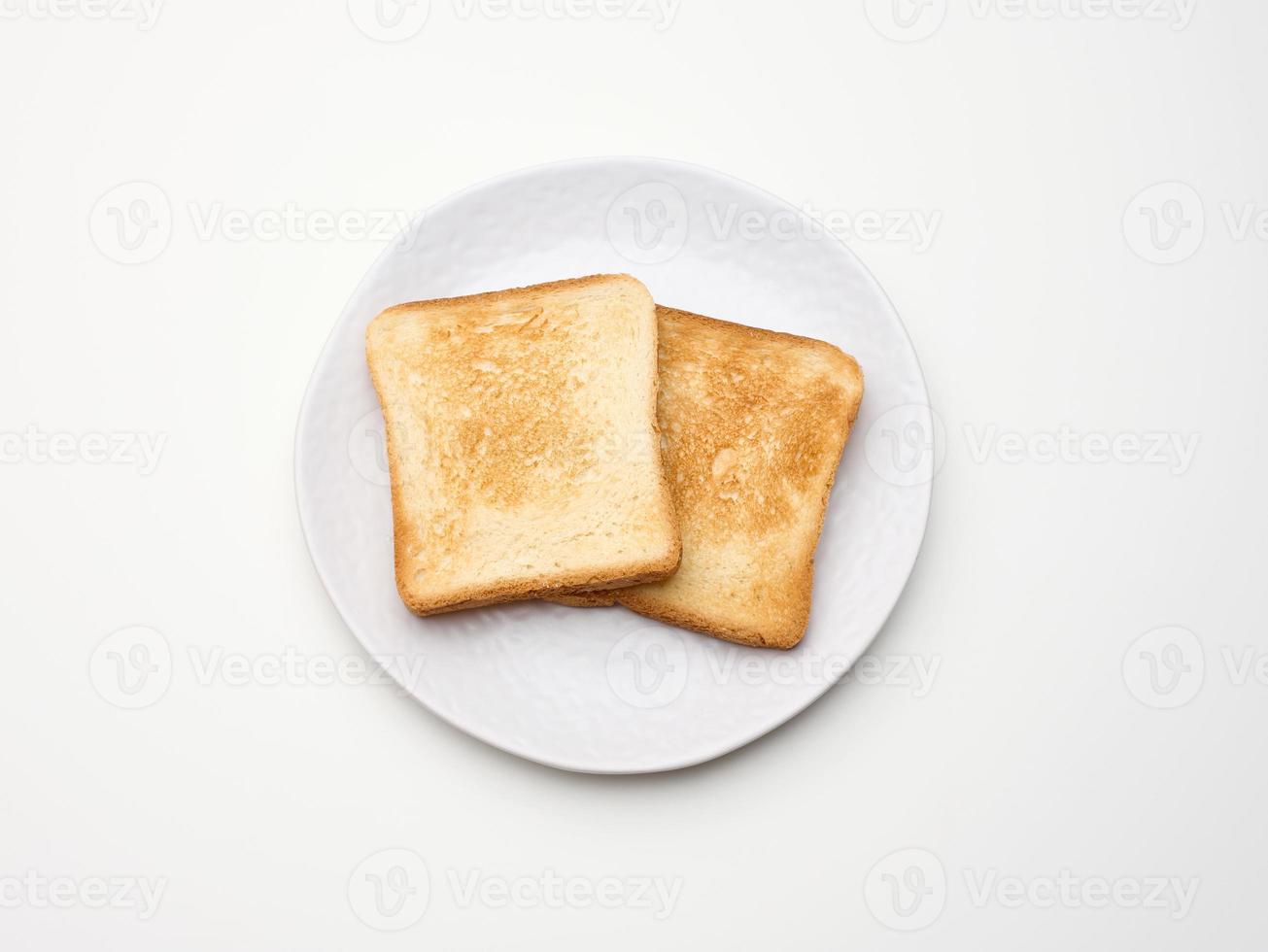 pedaços quadrados de pão torrado feito de farinha de trigo branca em um prato redondo. fundo de mesa branco foto