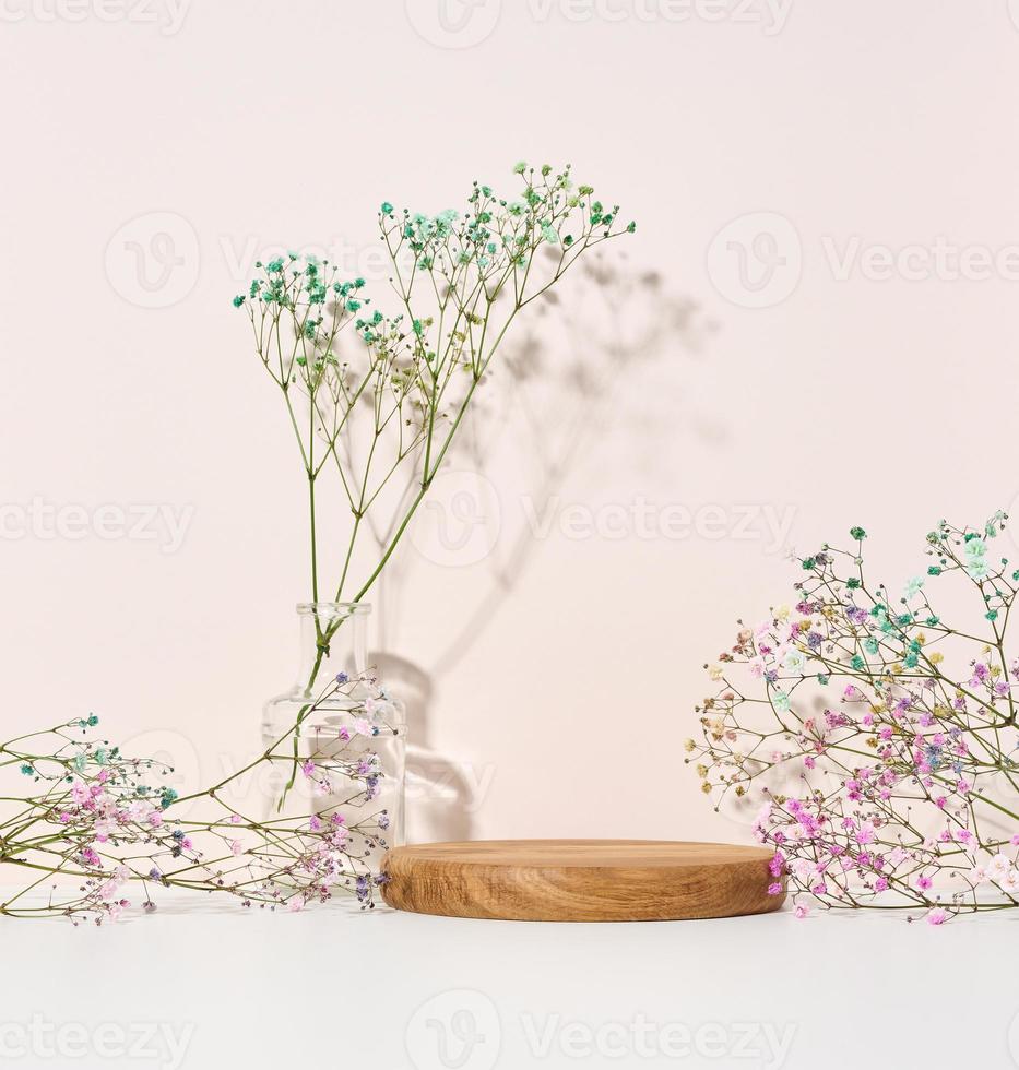 palco para exposição de produtos, cosméticos com pódio redondo de madeira e vaso de vidro com buquê de flores foto